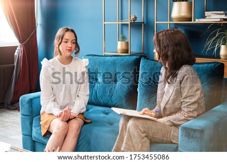 Young female psychologist working with teenager girl with depression problem in office. Sitting on the sofa. Female therapist. Royalty-Free Stock Photo #1753455086