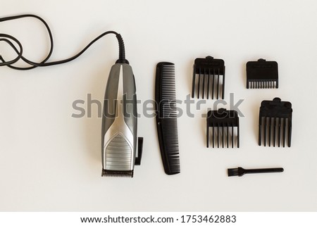 Slim Hair Clipper with stainless steel blades and different size combs of clipper and writing numbers on them on grey background