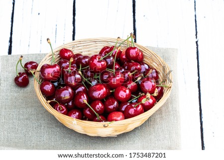 Cherry. Fresh sweet cherries and green leaves in wicker basket on white rustic background with empty space for text. Homegrown cherry. Agricultural background. Summer vacation. Healthy snack