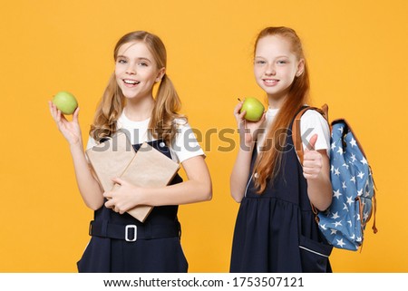 Girls 12-13 years old in white tshirt blue school uniform dresses hold schoolbooks isolated on yellow background children studio portrait Childhood kids education lifestyle concept Mock up copy space