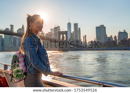 Girl enjoying magical sunset from the ferry  passing under the Brooklyn bridge