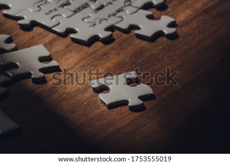 White puzzle piece on a walnut wooden table, selective focus.