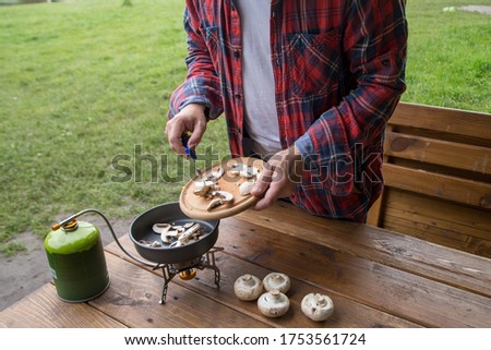 man slices mushrooms champignons for cooking at the campsite