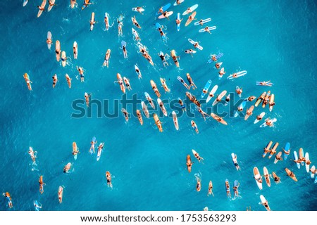 Aerial photo of big group of surfers paddle out together to support "black lives matter" at Hawaii. Colored surfboards in blue ocean top view.