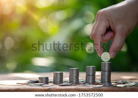 Coins a men's hand placed and sorted coins on a wooden board.