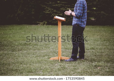 A shallow focus shot of a male near a speech stand with an opened book