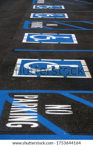A row of signs on the pavement for disability parking spots 