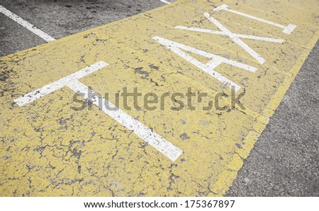 Taxi sign on asphalt, painted detail of a yellow road sign and safety information