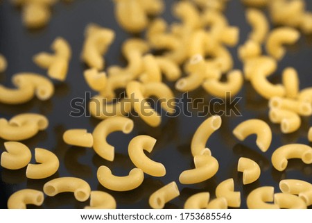Small pasta made from premium wheat flour and eggs fall on a dark table surface close-up grocery background macro photography