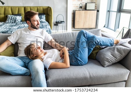 Cute couple relaxing on couch at home in the living room Royalty-Free Stock Photo #1753724234