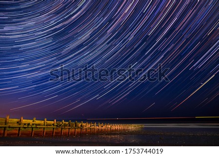 Hornsea Beach on the Yorkshire coast under a beautiful night sky, dramatic long exposure astrophotography showing beautiful stars & star trails Royalty-Free Stock Photo #1753744019