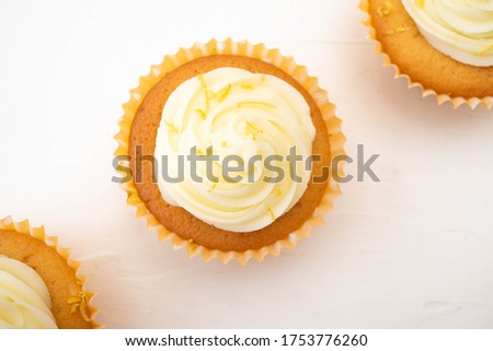 Three frosted cupcakes arranged on diagonal line through centre of the image.  Plain background with copy text space and shot in flat lay top down view.