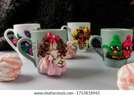 The original mug with decorative figurines made with their own hands. A lovely birthday present. Figures on the cup are fashioned hand made from colored clay. Colored background. High quality photo