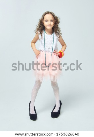 little girls play with their mother's makeup. they pose and try to be adults.Studio, white back