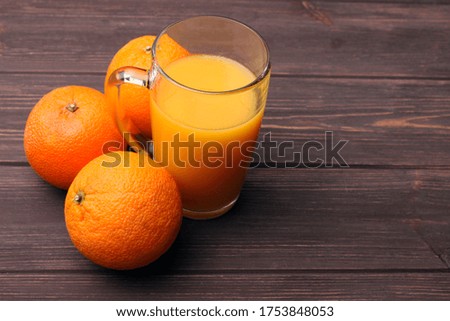 Freshly squeezed orange juice with three oranges on wooden table with space for text