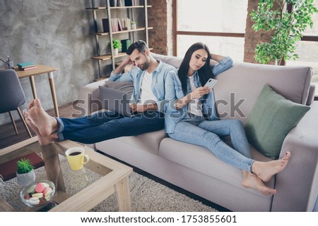 Full size photo of lazy tired two people man freelancer work remote laptop tired read project woman use smartphone chatting texting typing sit comfort cozy couch in house indoors