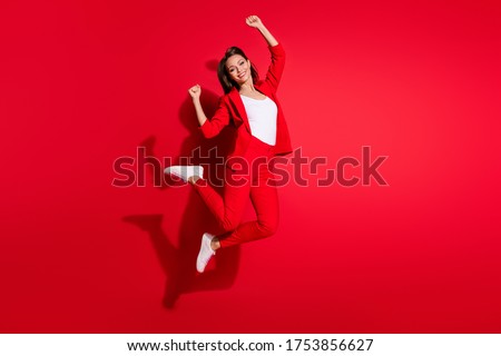 Full body profile photo of attractive lady worker having fun jumping high up good mood celebrate startup success wear blazer suit pants footwear isolated red color background