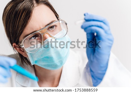 A blond medical or scientific researcher or doctor using looking at a clear solution in a laboratory