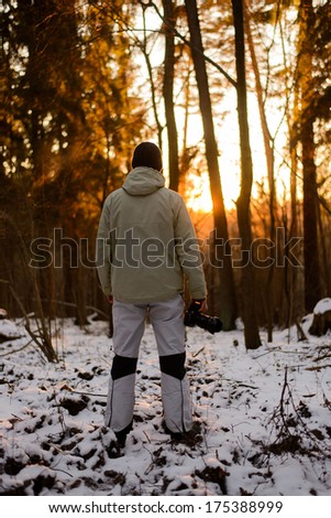 photographer holds his camera and looking to a beautiful winter landscape