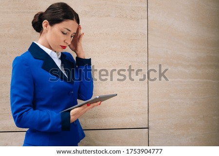 The business lady clutched her hand by the face in surprise. The manager looks into the digital tablet and gets upset. Dismissal from work in quarantine. High quality photo