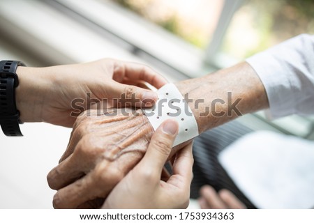 Hands of senior with analgesic sheet,chinese plaster to stick on the wrist of the old elderly to relieve muscular pain,plaster cover the patient's pain area on skin to release sprain,body ache relief Royalty-Free Stock Photo #1753934363