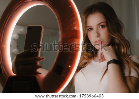 Stock Photo - Photo though the ring lamp of young girl take a selfie.  In the beauty salon doing makeup.
