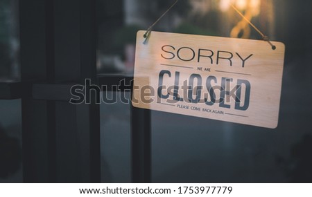 Wooden signs with the symbol meaning The shop is closed. Please come back again. Hanging on the glass front door in the evening due to the incident at COVID 19, symbolic concept