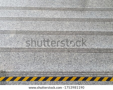 Yellow and black safety bars are installed on the stairs at the highest level to prevent careless walking since they are not aware of the different levels of space. Warning tape is a safety symbol.