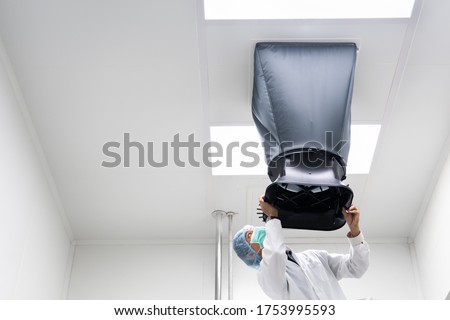 The unidentified operator is using the capture hood balometer to measuring the air velocity and volume of supply air from HVAC system in the clean room. Royalty-Free Stock Photo #1753995593