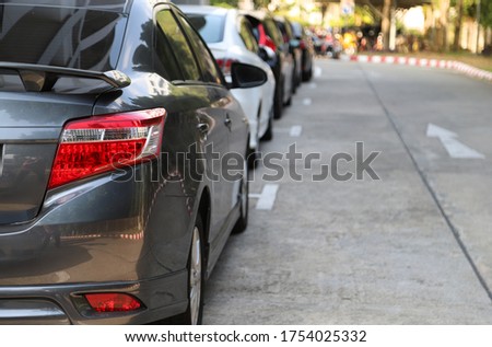 Closeup of rear, back side of black car with  other cars parking in outdoor parking area beside the street with natural background in sunny day.
