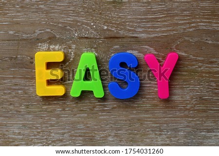Text made in multicolored magnetic letters. EASY. Scratched wooden grunge background.