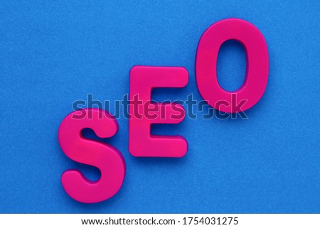 Text made in multicolored magnetic letters. SEO. Blue background