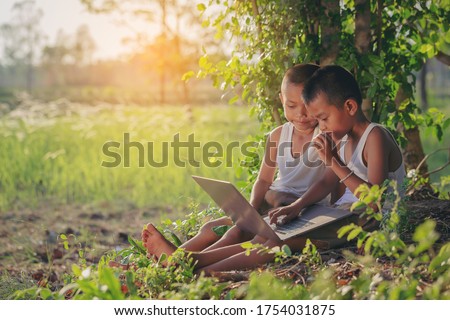 Asian country boys enjoying outdoors using laptop for self learning. Technology for education concept. Royalty-Free Stock Photo #1754031875