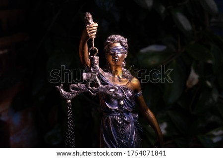 Themis statue, concept of law and justice on the background of a green flowerpot. Close up. Royalty-Free Stock Photo #1754071841