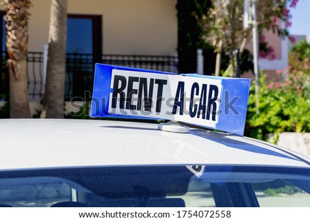 Blue sign Rent a car on top of rental vehicle. Mobile advertisement of transport company. Offer for tourists.