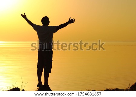 Blurred silhouette of a man on the seashore watching the sunset. Soft focus