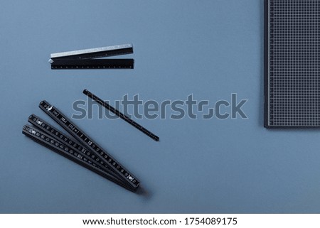Notebook with rulers on blue background. Various measuring rulers, sticks, tape measures on grey background. Concept of work or education.