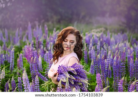 A girl in a Lupin field with a hat and a pink dress