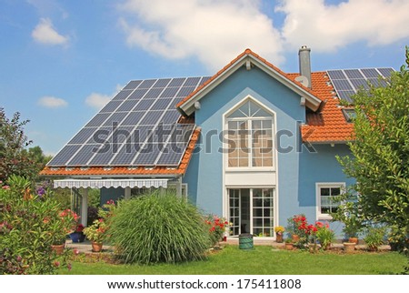 modern new built house and garden, rooftop with solar cells, blue front with lattice window. Royalty-Free Stock Photo #175411808