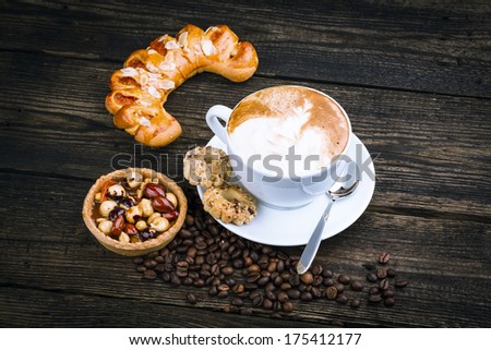 cup of cappucino and cakes on dark background