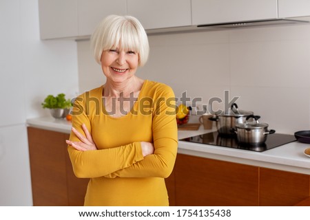 Happy aging smile concept. Female woman stand crossed hands isolated at kitchen light background. One adult person people advertise homemade cookies food. Pictures with copy space horizontal. Cute 60s