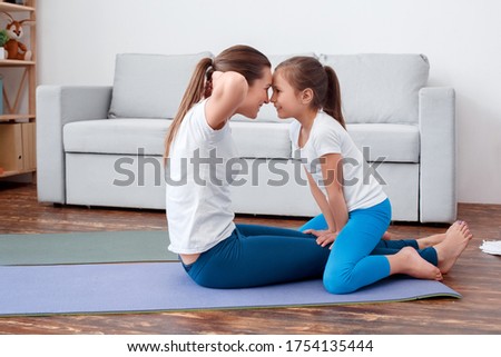 Family fools on weekend playing sports engaged fitness, yoga, exercise at home interior. Horizontal. Active training. Healthy concept. Kid woman swing press on stomach lie mat. Lifts body up, twisting