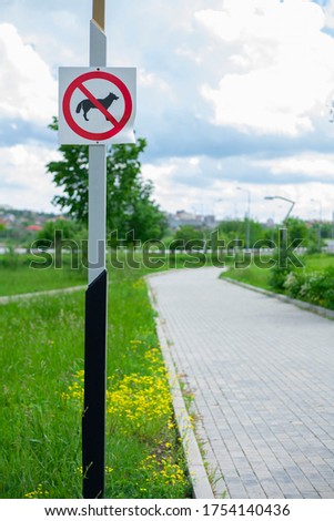 A sign on a post that prohibits walking dogs in a park. Dog walking is prohibited. Not a place for dog walking.