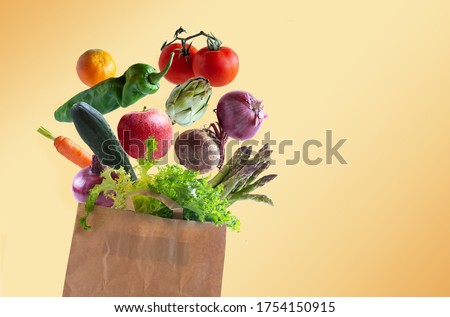 Vegetables flying in recyclable paper bag with copy space, orange background
