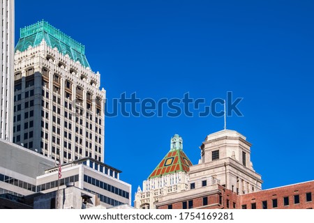 View of rooftops of downtown Tulsa Oklahoma -mixture of Art Deco and modern buildings with an American flag against very clear blue sky