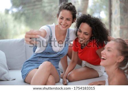 A group of friends smiling while taking a selfie and sitting indoors