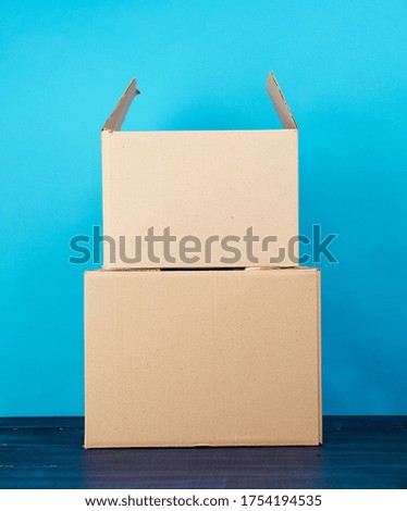 stack of cardboard boxes of brown kraft paper on a blue wooden table, moving concept