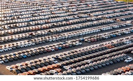 New cars stand in even rows in the giant parking lot of a car factory in the evening at sunset, aerial view. Royalty-Free Stock Photo #1754199686