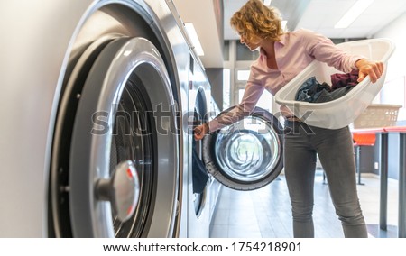 inserting dirty clothes into the washing machine in the laundry room Royalty-Free Stock Photo #1754218901