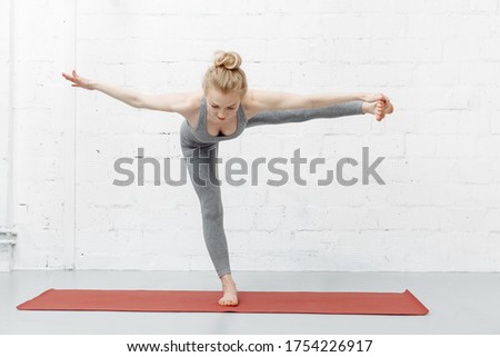 Young attractive woman practicing yoga, stretching in Elbow Bridge exercise, Urdhva Dhanurasana pose, working out, wearing sportswear, black tank top, shorts, indoor full length, home interior, cat